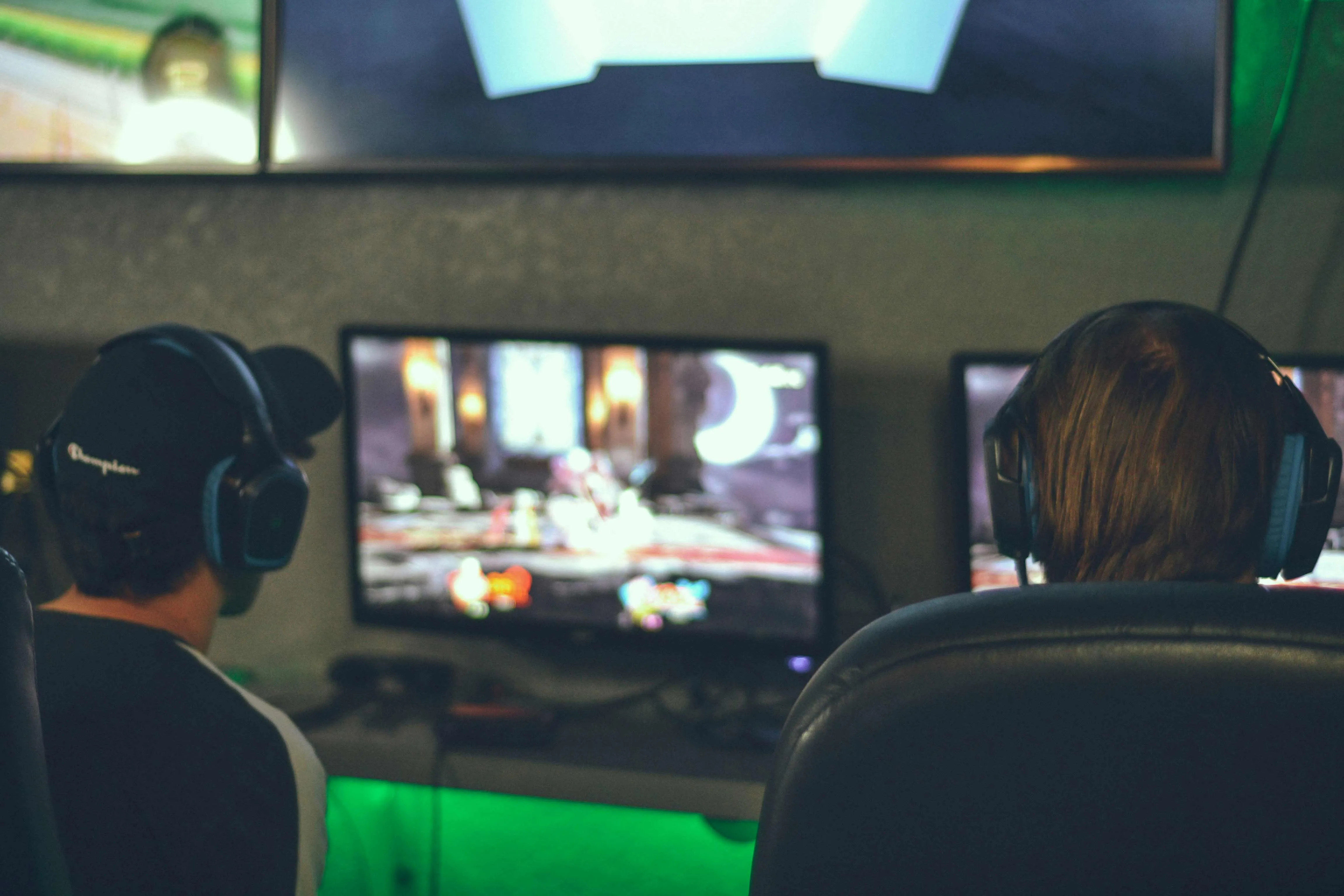 Two gamers sitting in front of the screens playing a video game together
