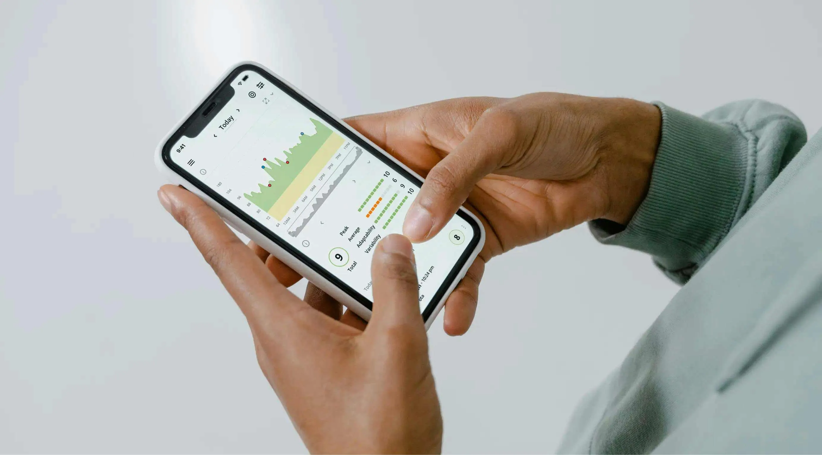 A zoomed in shot of person's hands holding a smartphone. On the screen, data points are visible in shape of charts and graphs.